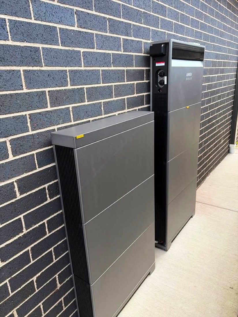 Anker SOLIX battery with a second expansion stack beside it against a dark brick wall