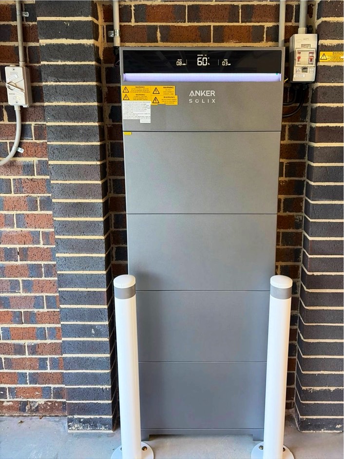 Anker SOLIX battery between two white bollards in a brick garage