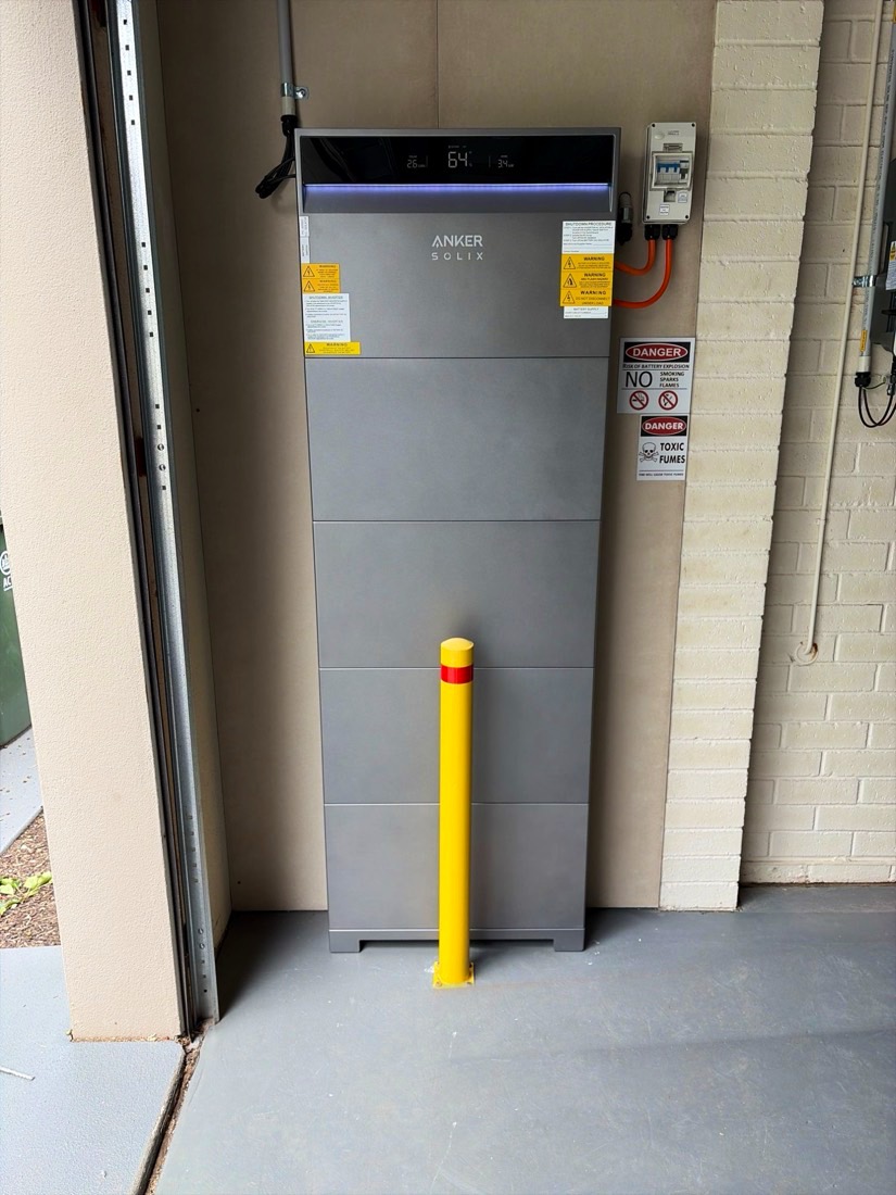 Anker SOLIX battery in a garage behind a yellow safety bollard