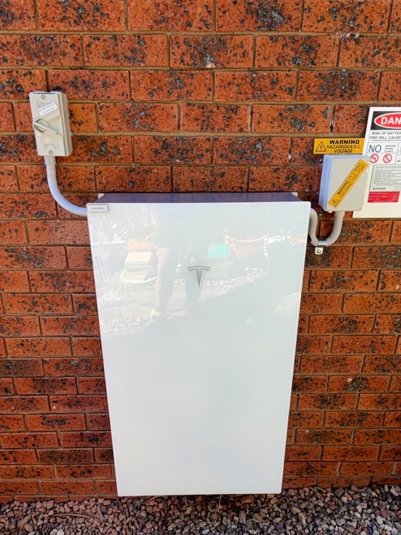 White Tesla Powerwall 3 on a red brick wall in Stirling