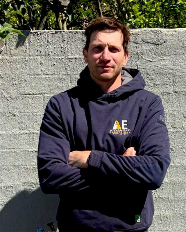 Jacob in an Advanced Electrical hoodie, arms crossed, in front of a rendered wall